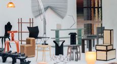 A series of experimental chair, table, and stool designs, set inside a white-painted gallery with warm lighting and white walls.