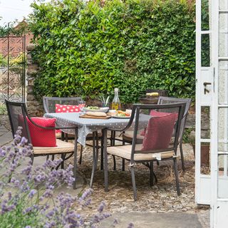 outdoor dining table with red cushions and flower plants