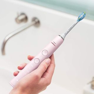 Philips Sonicare DiamondClean review: pink electric toothbrush in hand over sink