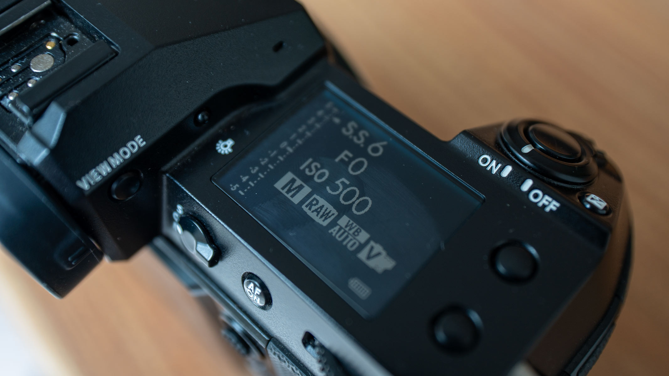 A close-up view of the secondary LCD monitor on the Fujifilm GFX100S II, on a wooden table.