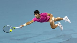 Carlos Alcaraz of Spain dives for the ball against Jannik Sinner of Italy at the Miami Open