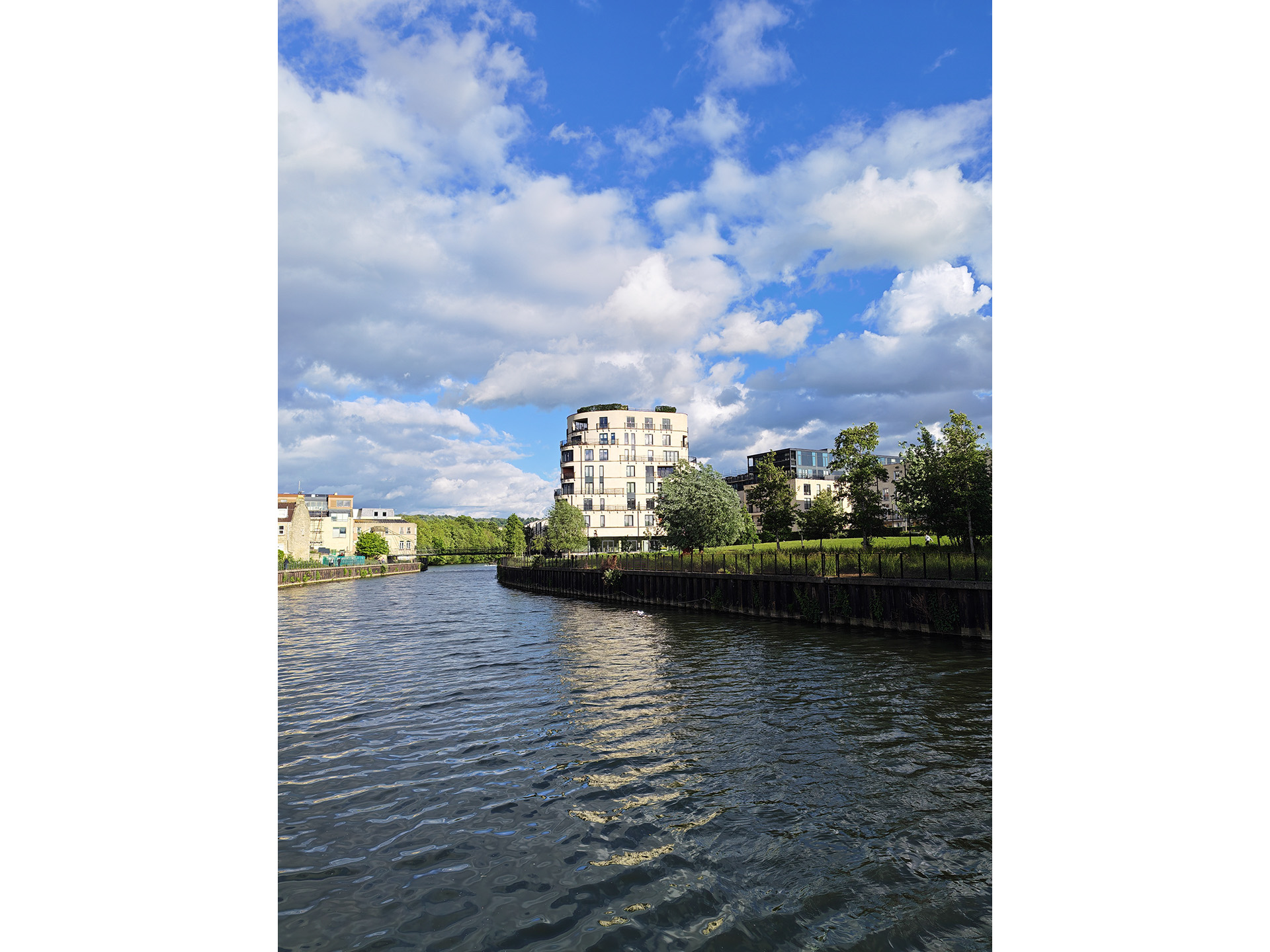A tall block of flats by a river at a 1x zoom.