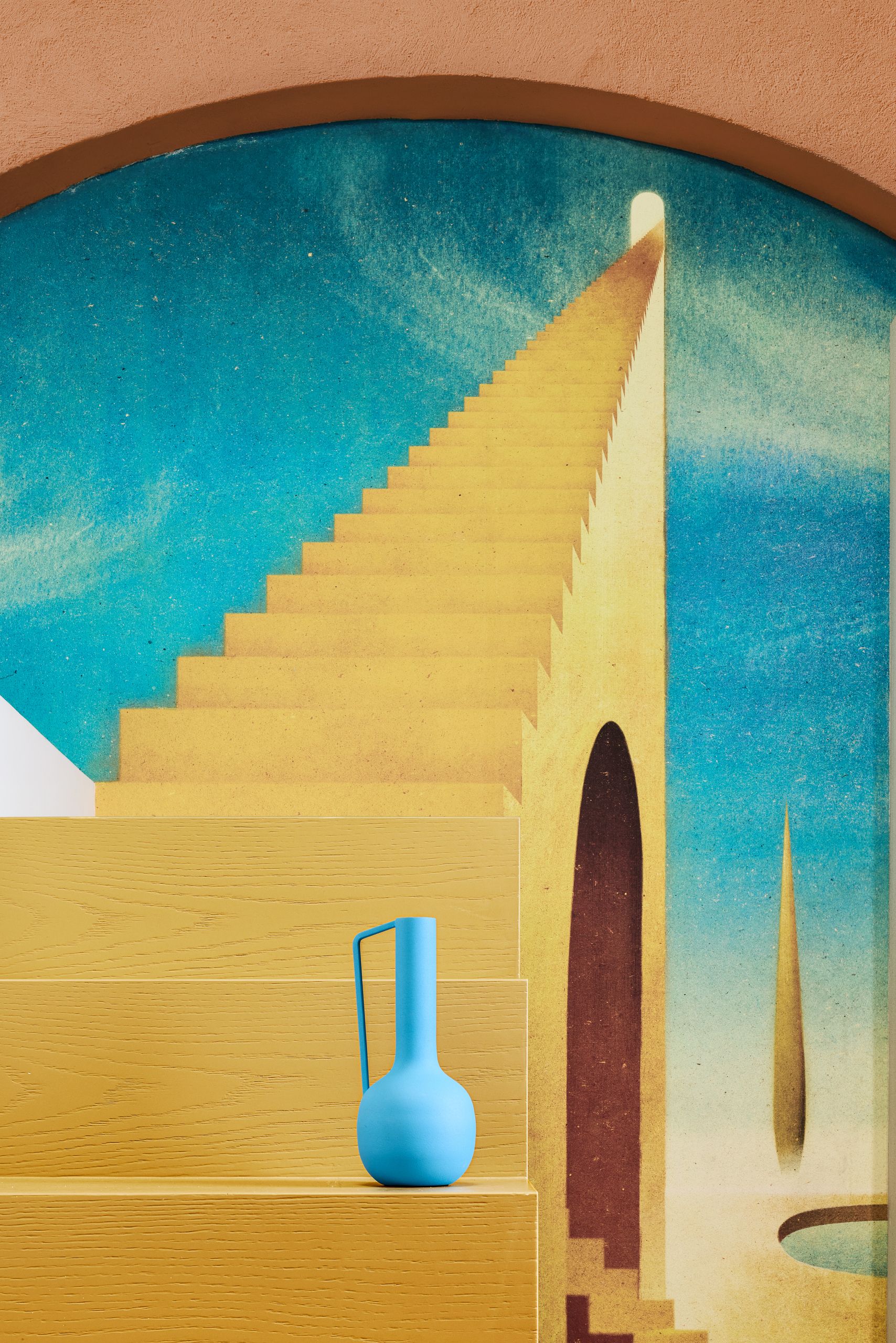A close-up of the yellow stairs leading up to the loft bed and a blue vase blending into the 'Mysterious Baths' mural by Owen Gent