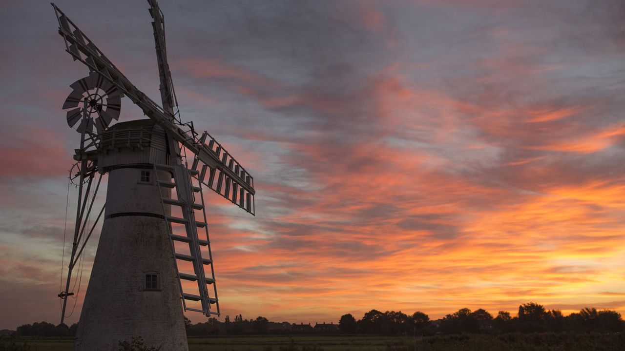 The sun rises behind Thurne Mill, a former drainage mill on the Norfolk Broads