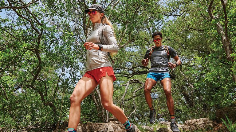 Two runners in a forest wearing Garmin Fenix 7 smartwatch