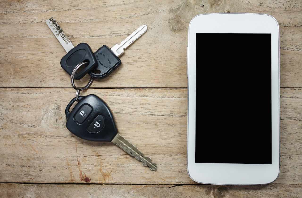 Mobile phone and car remote keys on wooden background