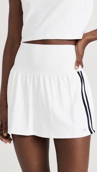 a model wears a white tennis skirt with black stripes down the side