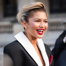 Zendaya smiling at photographers wearing an oversize blazer jacket