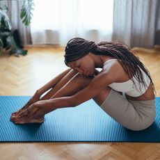 A woman stretching on a yoga mat in gym clothes