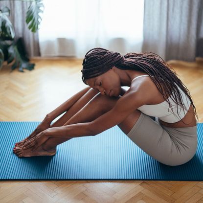 A woman stretching on a yoga mat in gym clothes