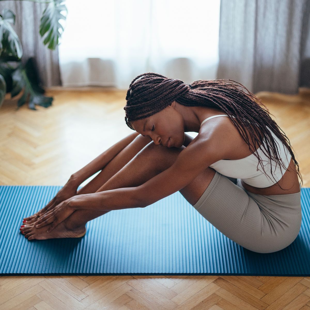 A woman stretching on a yoga mat in gym clothes