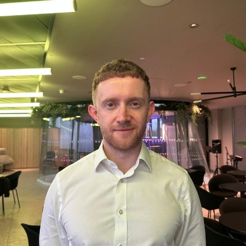 Image of a man in a white button-down standing in an office building.