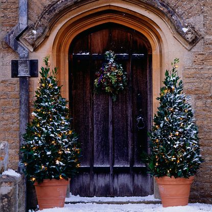 doorway with bricked wall and wreath and pots