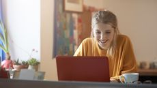 A young woman in an orange jumper using a laptop with an orange case