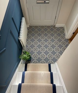 blue and cream smalled tiled hallway with cream and blue runner on stairs