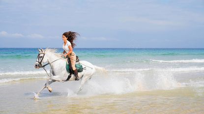 A woman riding a horse on Comporta beach
