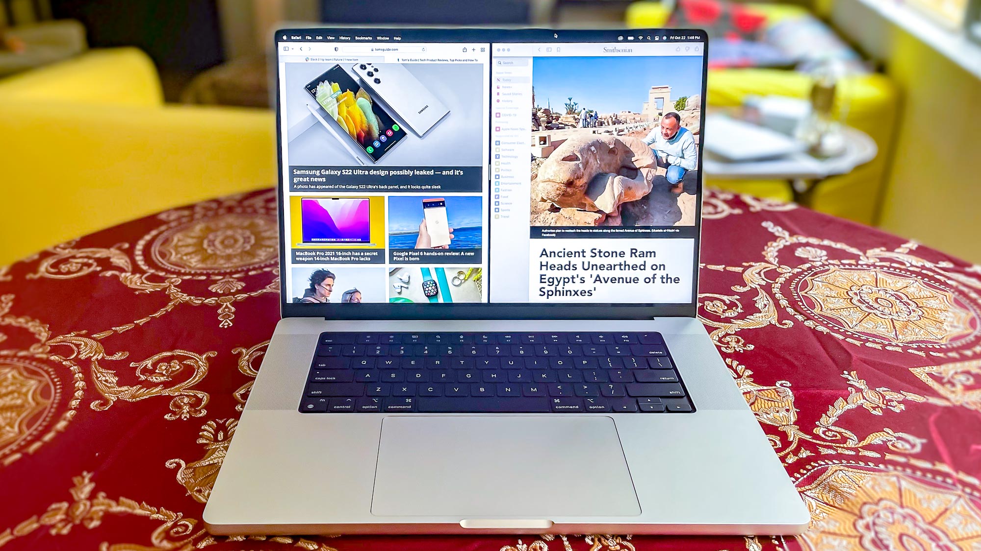 MacBook Pro 2021 (16-inch) sitting at a table showing two web pages side by side