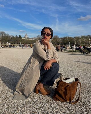 @lenafarl wearing trench coat, jeans, and suede clogs with suede bag.