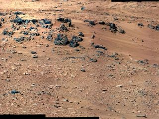 This patch of windblown sand and dust downhill from a cluster of dark rocks is the "Rocknest" site, which has been selected as the likely location for first use of the scoop on the arm of NASA's Mars rover Curiosity. This view is a mosaic of images taken by the telephoto right-eye camera of the Mast Camera (Mastcam) during the 52nd Martian day, or sol, of the mission (Sept. 28, 2012), four sols before the rover arrived at Rocknest.
