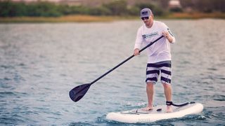 7 outdoors activities for weekend family fun: man paddleboarding on a lake
