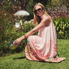 A model wearing a light pink flowy dress with botanical patterns around the bottom, from New Look. 