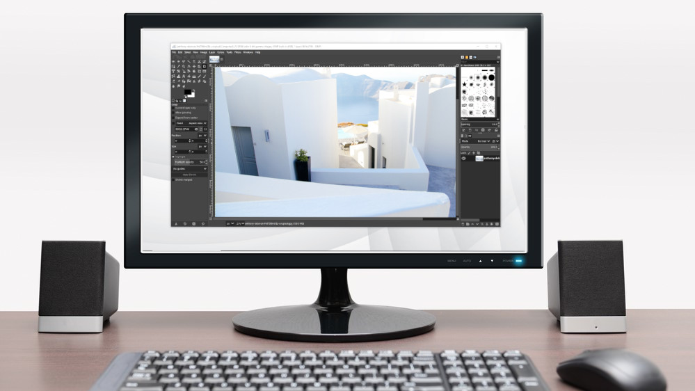 En stasjonær PC med tastatur og mus, med en skjerm som viser GIMP kjørende