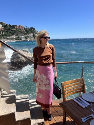 Eliza Huber wearing a brown sweater and pink printed pencil skirt at a restaurant in Nice.
