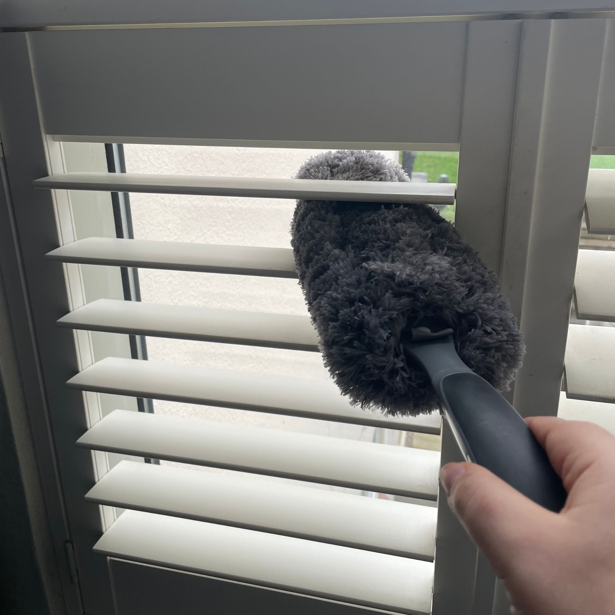 Using a feather duster to clean plantation shutters