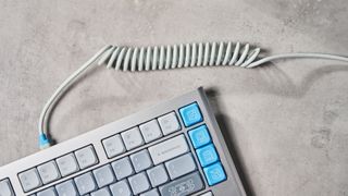 The NuPhy Nos75 mechanical keyboard on a stone surface with a blue background