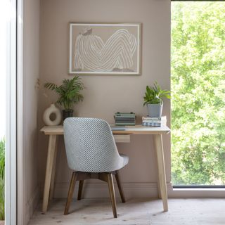 wooden desk in front of wall and window with plants on