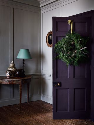 Natural foliage wreath on purple door with green ribbon