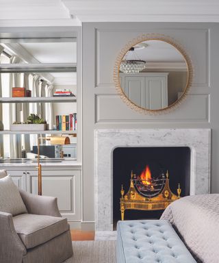 A cream living room with a marble fireplace below a gold circular mirror