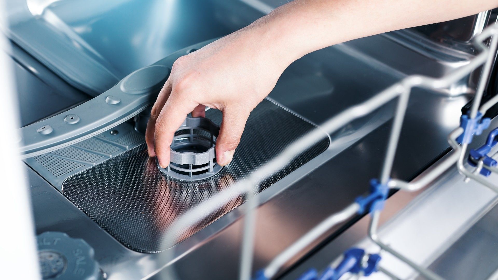 person twisting out the filter on the inside of the dishwasher