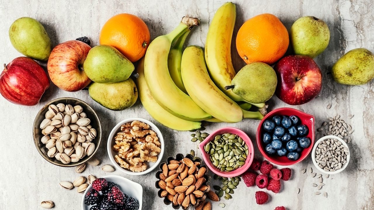 A variety of fruits with bowls of nuts