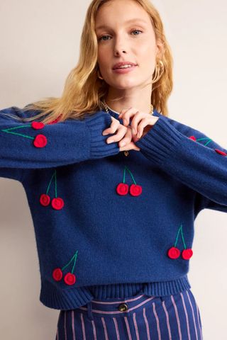woman wearing blue jumper with knitted cherries all over