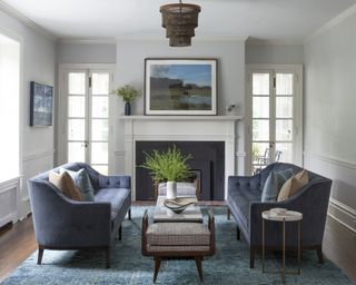 A living room with dark blue sofas, a cyan blue rug and a white fireplace
