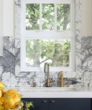 kitchen sink with marble backsplash and window