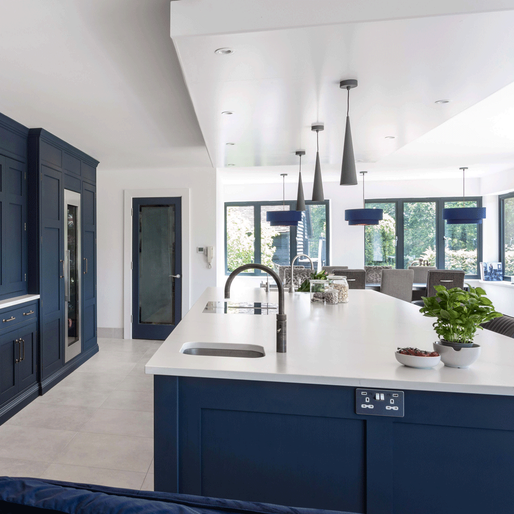 Large open plan kitchen with white countertop island and blue cupboards