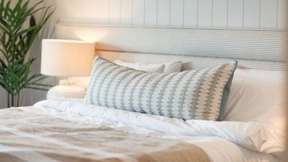 A kingsized bed close up, with two pillows and a cushion 