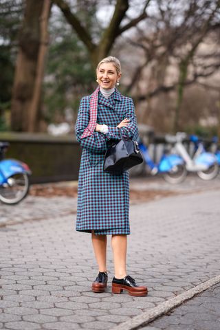 A woman at fashion week in a checked jacket and loafers