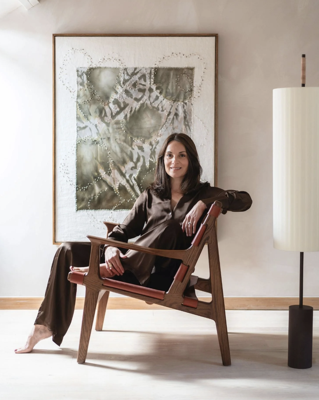 Gemma Tucker sitting in a mid-century chair with artwork on the wall behind