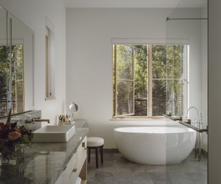 A minimalist bathroom with a large window overlooking greenery
