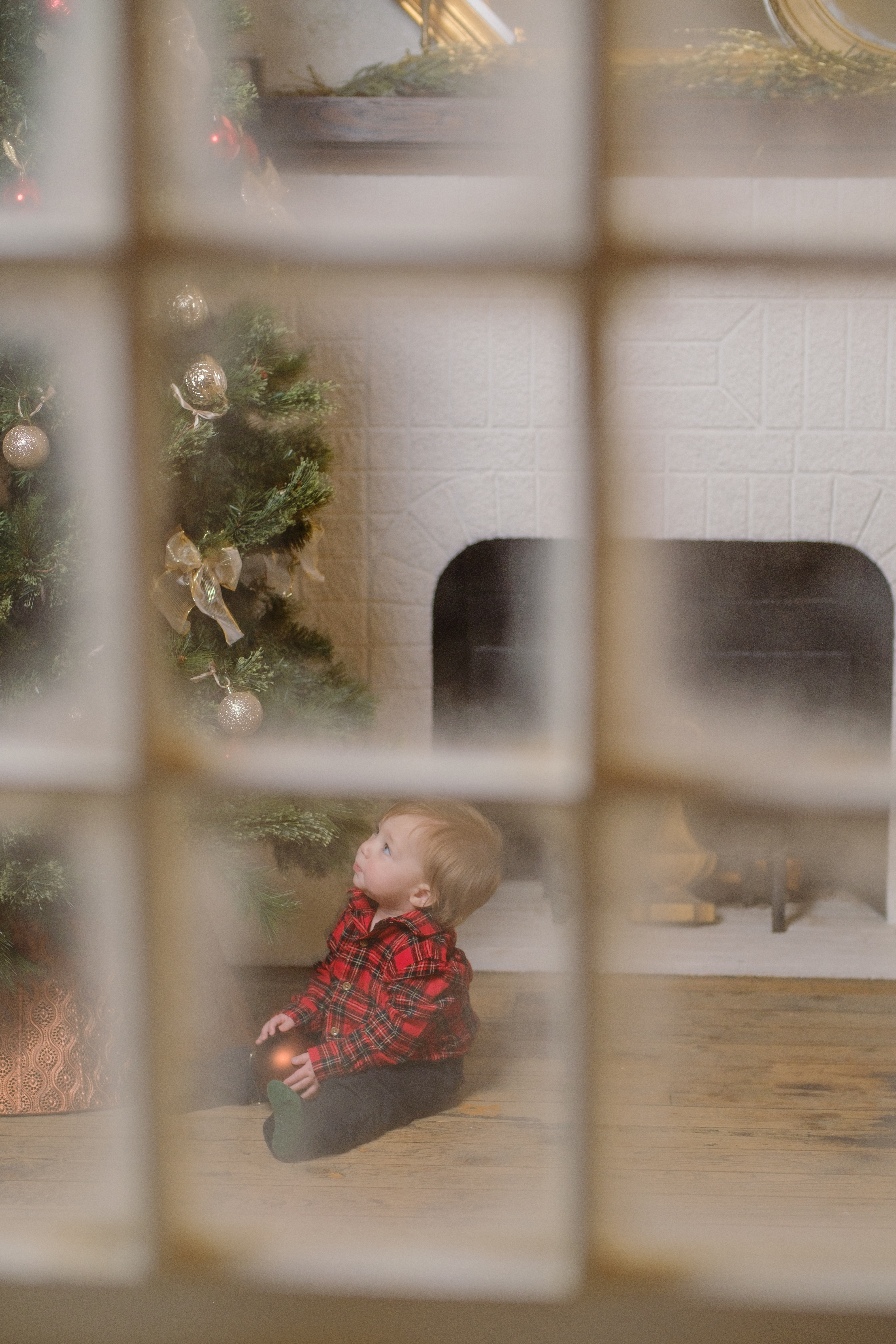 A child with a toy train framed by a snowy Christmas window