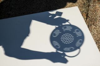 Photo of images of the solar eclipse on 8/21/17 projected by a colander. The solar eclipse is at 80% and show up as little crescents.