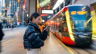 Asian woman using mobile phone during waiting for train at railway station
