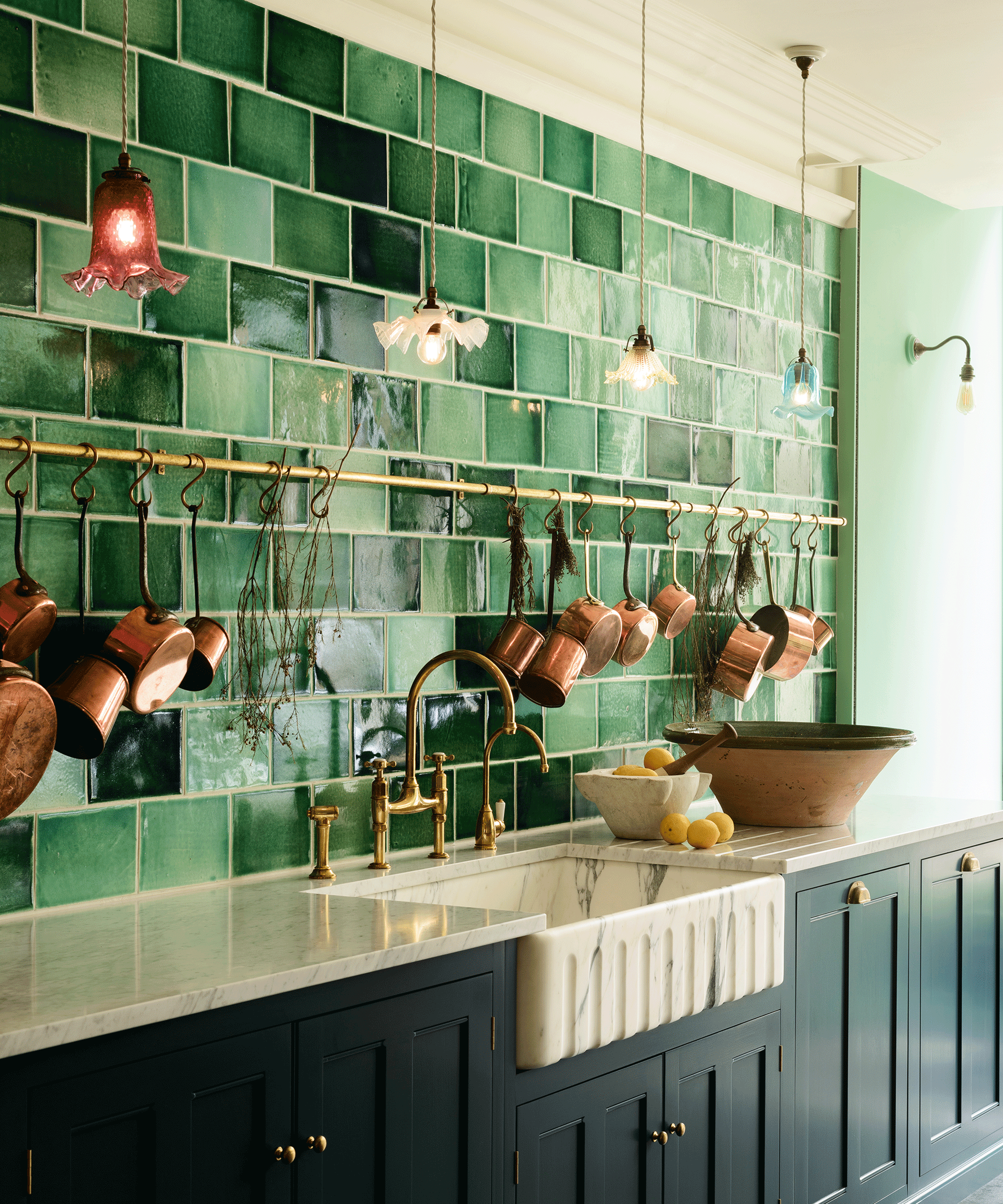 green kitchen with green tiles and pretty pendants hanging over the worktop