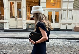  @elizagracehuber wearing an ivory pillbox hat with a navy dress and Saint Laurent black Manhattan bag on the streets of SoHo in NYC.