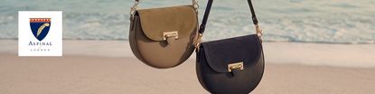 aspinal of london logo top left with two shoulder bags hanging on a line on a beach