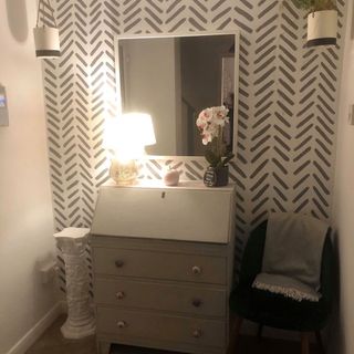 a hallway with white wall and striped print wall paper and a large mirror