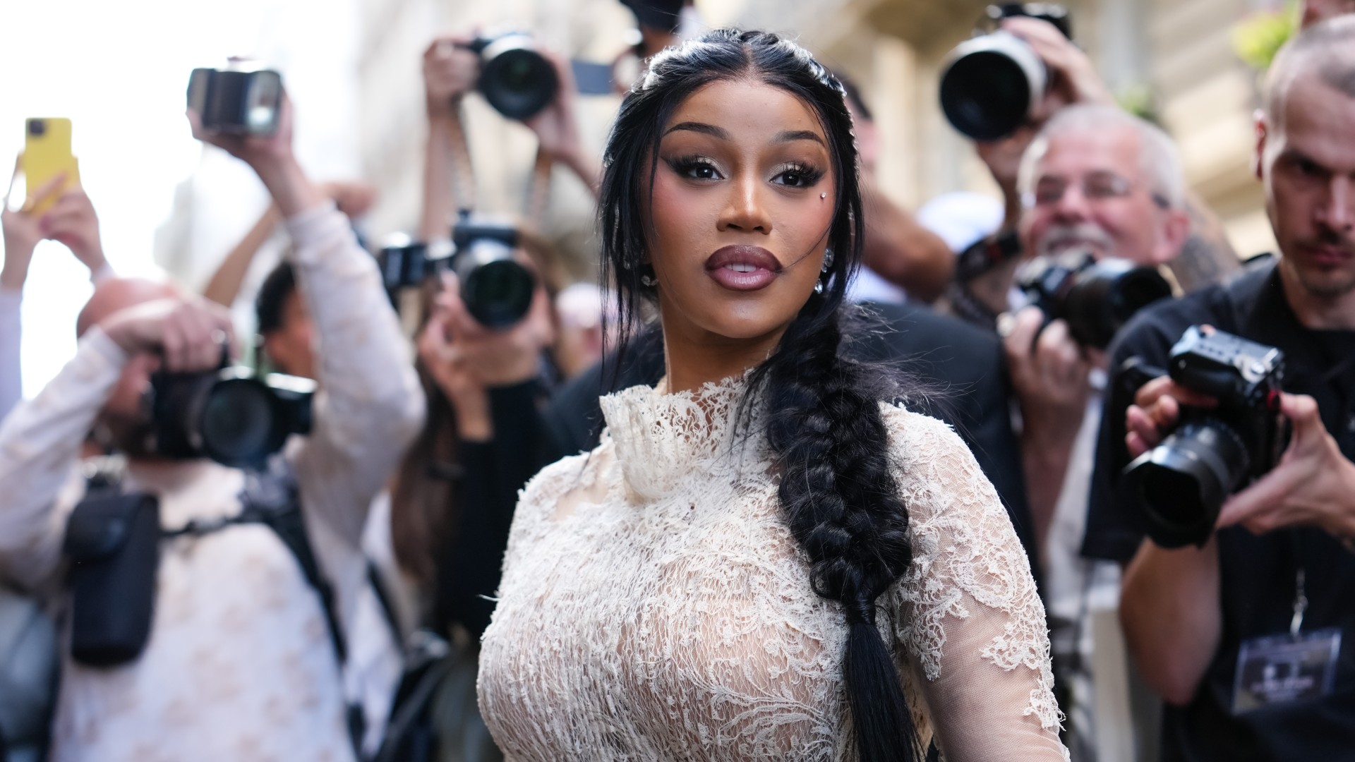 cardi b standing in front of a crowd of paparazzi